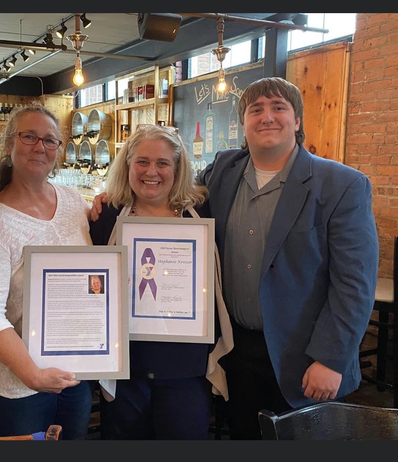Stephanie Kresser holding a framed 2022 Social Responsibility Award.