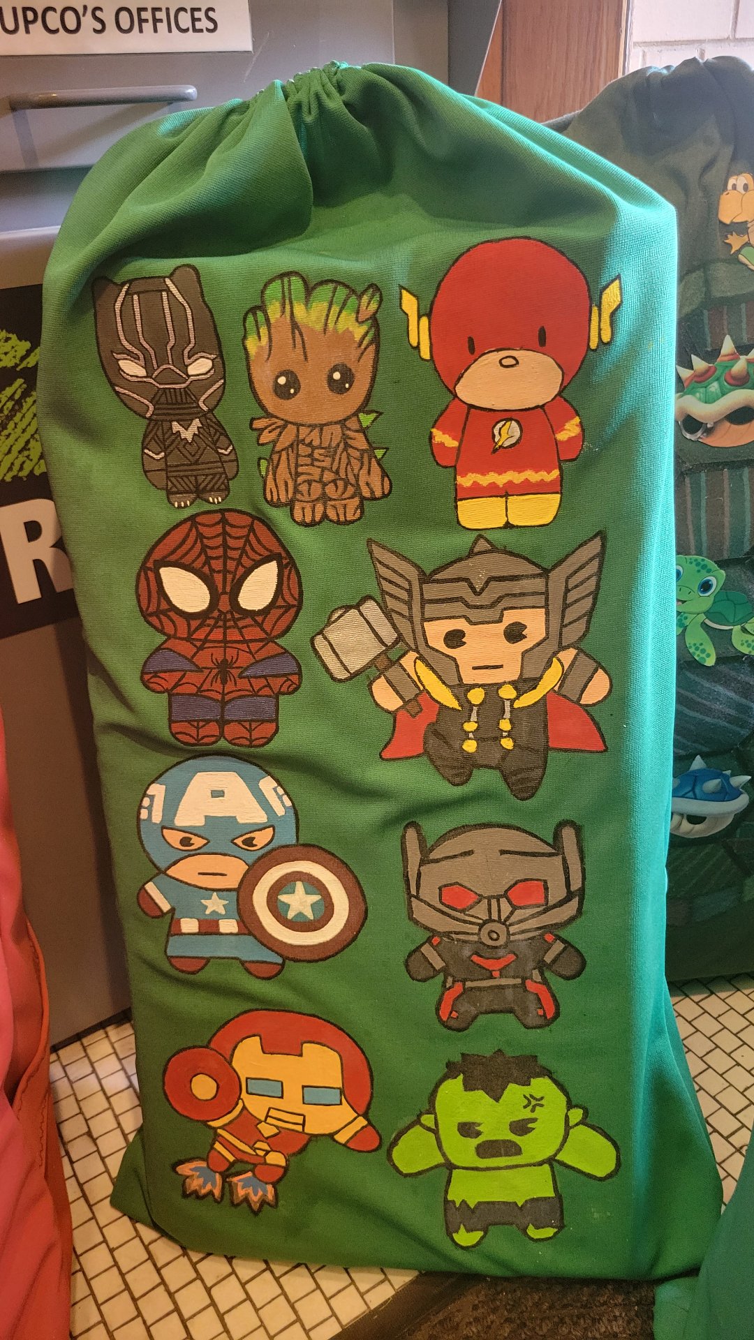 Close-up of a green MySleeper bag hand-painted with colorful superhero characters.